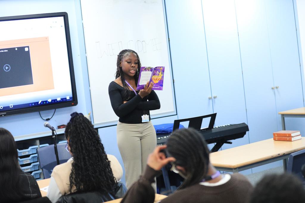 A student leader reading from TeeVo while others listen during a Spark Christian Society meeting